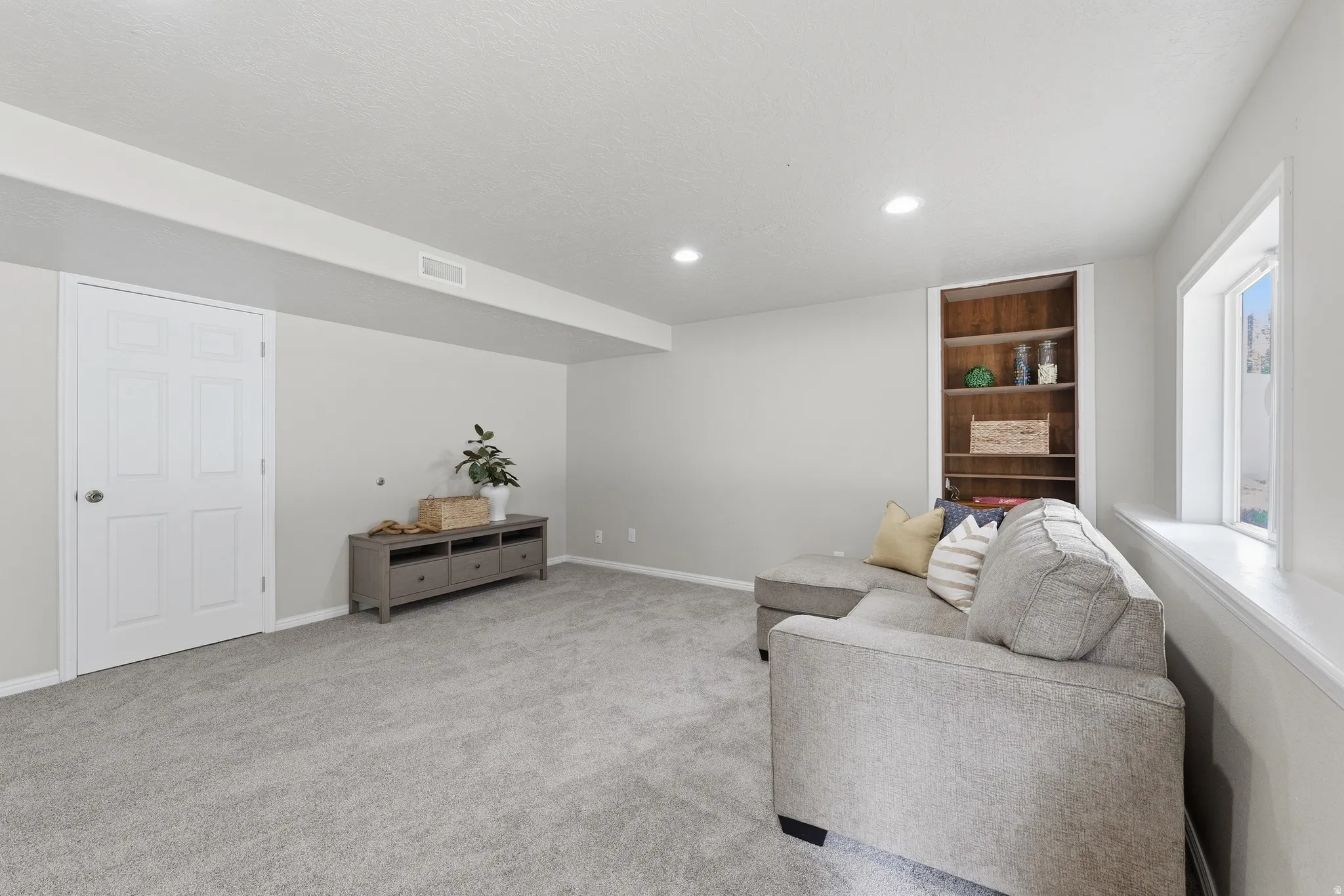 Basement great room with recessed lighting and storage access.