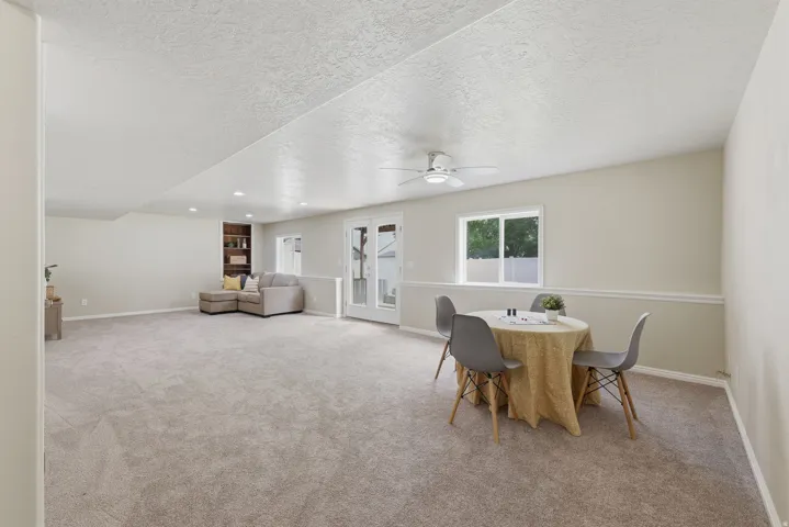 Expansive carpeted room featuring a ceiling fan, recessed lighting, and access to backyard