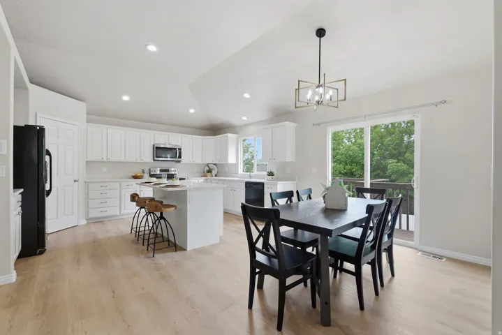 Open-concept kitchen with wood-finish LVP flooring, white cabinetry, a center island, quartz countertops and recessed lighting