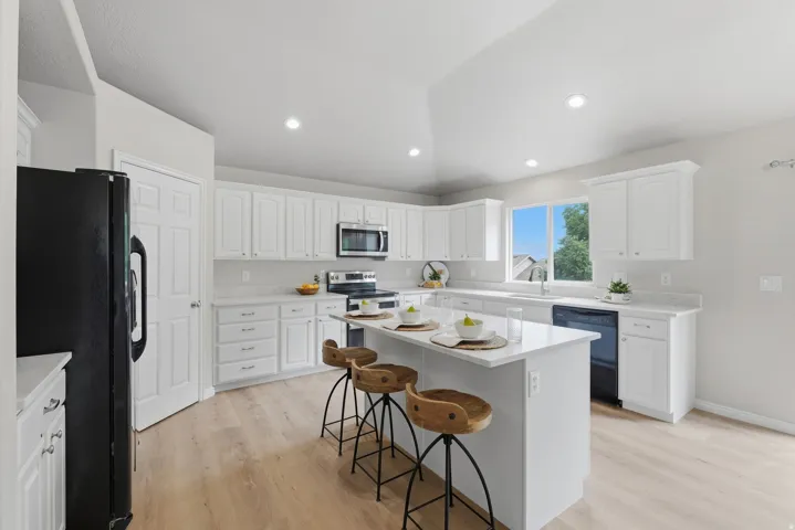 Kitchen featuring white cabinetry, quartz countertops, wood-finish LVP flooring, recessed lighting, and a large window
