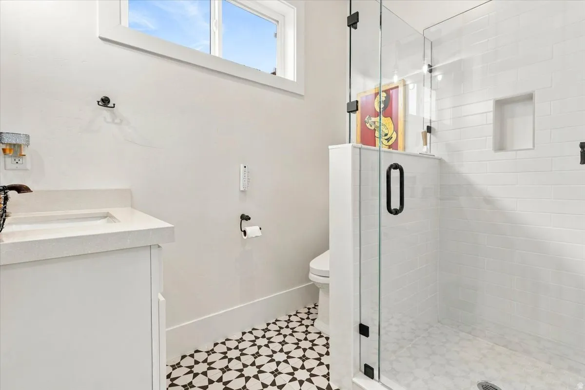 White subway tile shower with a built-in niche, glass enclosure, and matte black hardware