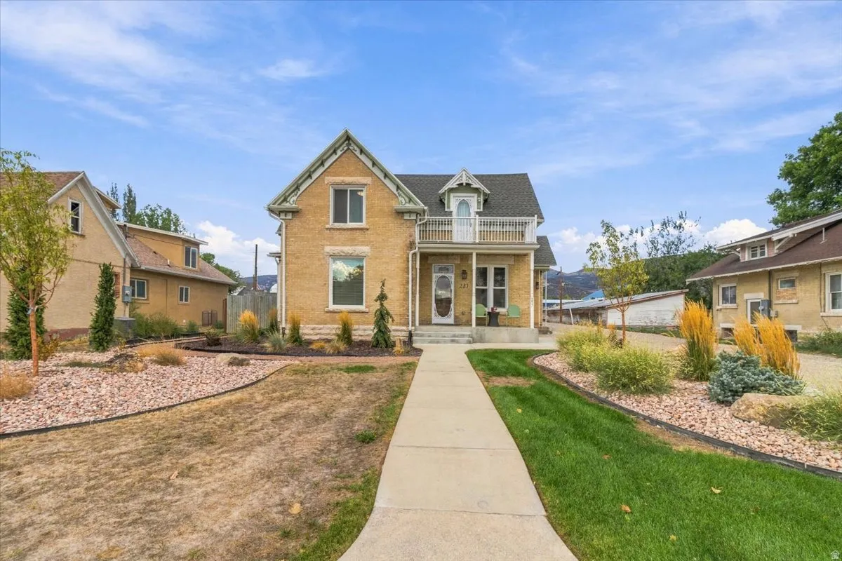 Classic Colonial-style residence with a distinctive peaked roofline and gabled entry, featuring a pale yellow exterior with contrasting trim and dark shale-colored roofing
