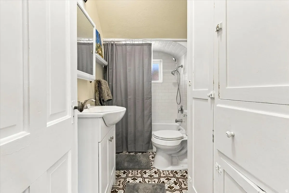 White paneled cabinetry, patterned tile flooring, and a shower-tub combination with subway tile surround