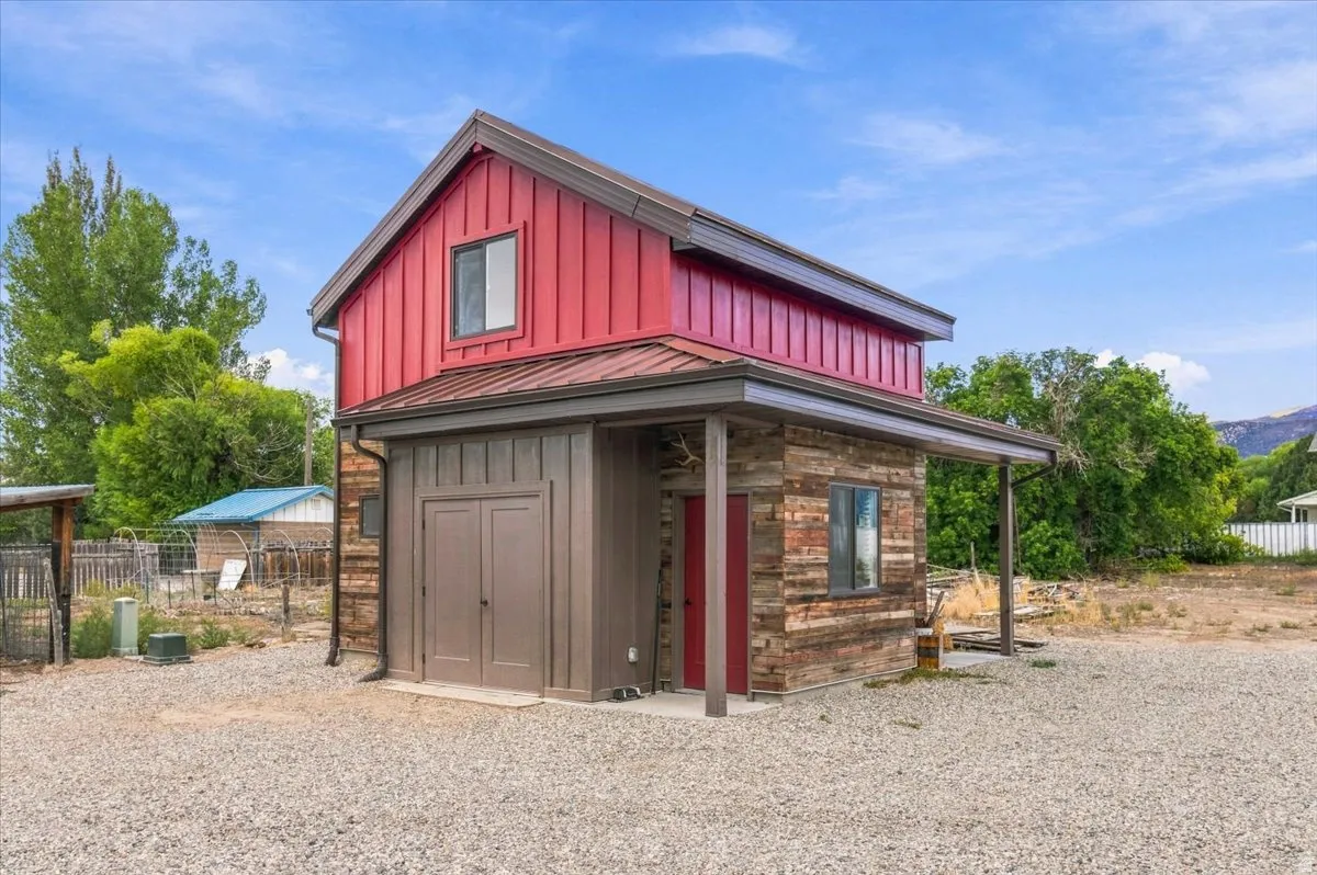 Red vertical siding with a contrasting wood-finish lower level, metal roof, covered entry, and double doors