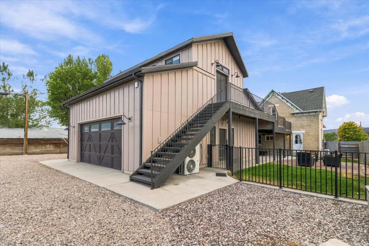 Board and batten exterior with an attached garage, upper-level balcony, and exterior staircase