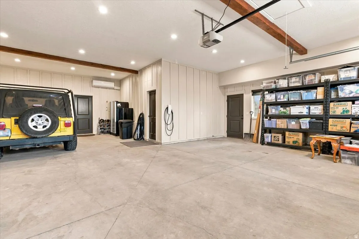 Spacious garage featuring a concrete floor, recessed ceiling lighting, exposed wood ceiling beams, and a mini-split climate control system