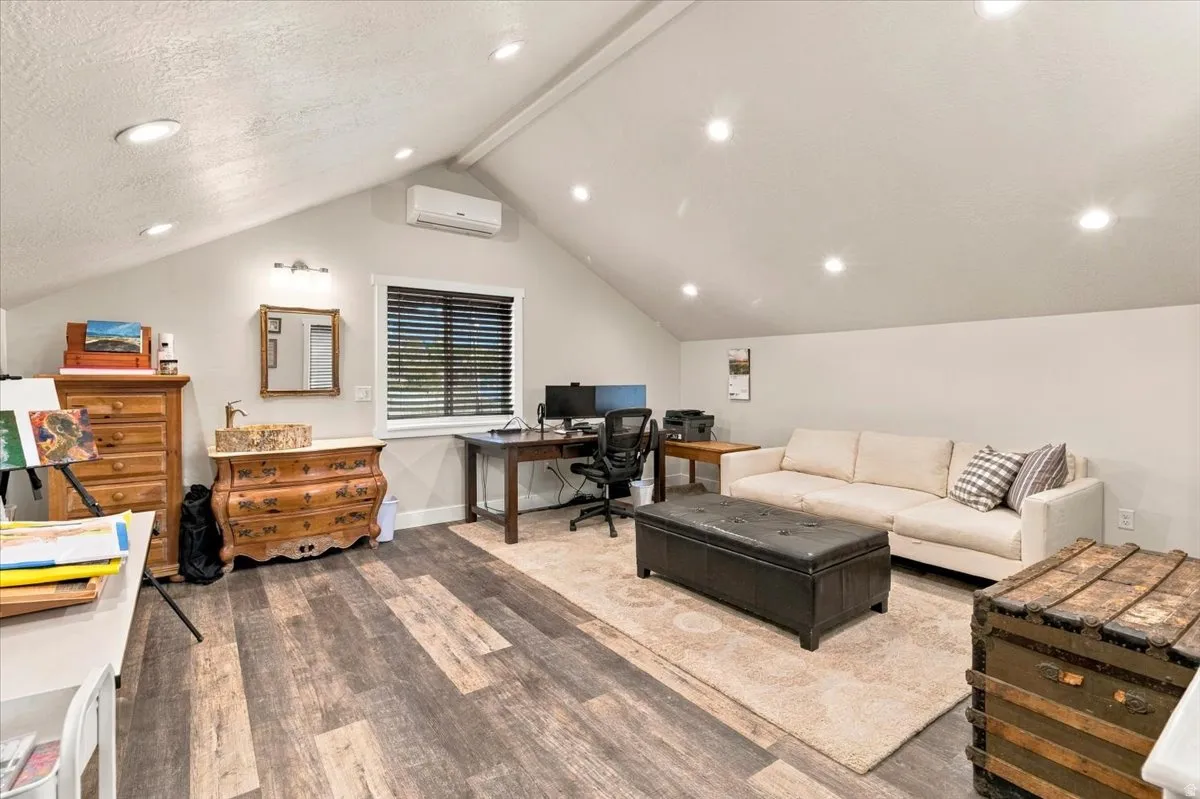 Vaulted ceiling with recessed lighting, wood-finish flooring, and a mini-split climate control system