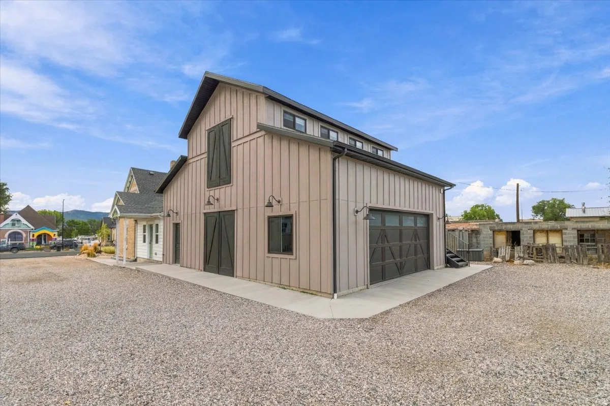 Barn-style exterior featuring vertical siding, a large overhead garage door, and multiple exterior lighting fixtures
