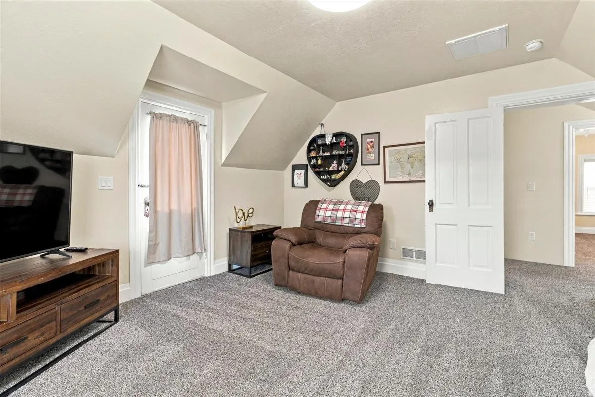 Sloped ceilings, recessed lighting, neutral wall tones, and gray carpeting
