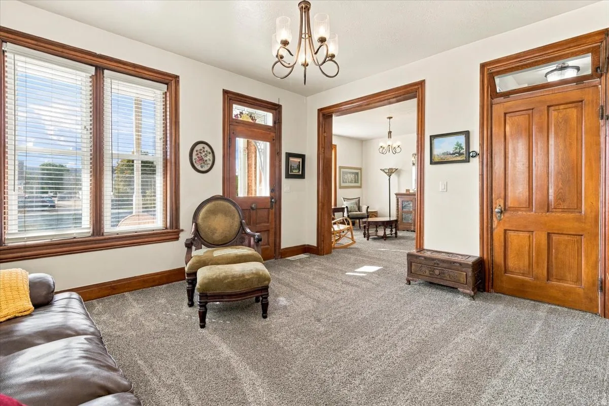 Carpeted interior with wood-trimmed windows, a wood-paneled door, and a chandelier lighting fixture