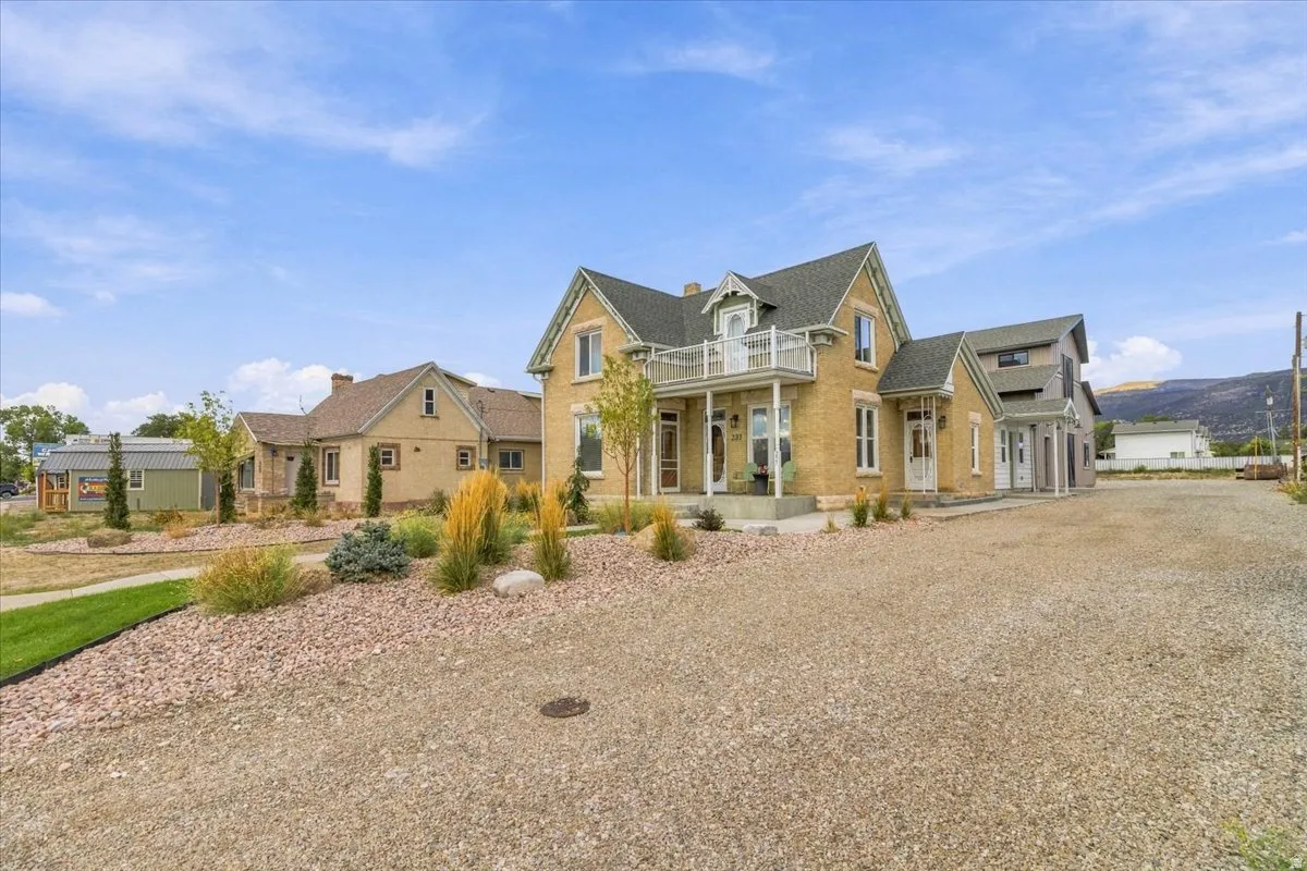 Elegant farmhouse-style residence featuring a cream-colored exterior with gabled rooflines and multiple chimneys
