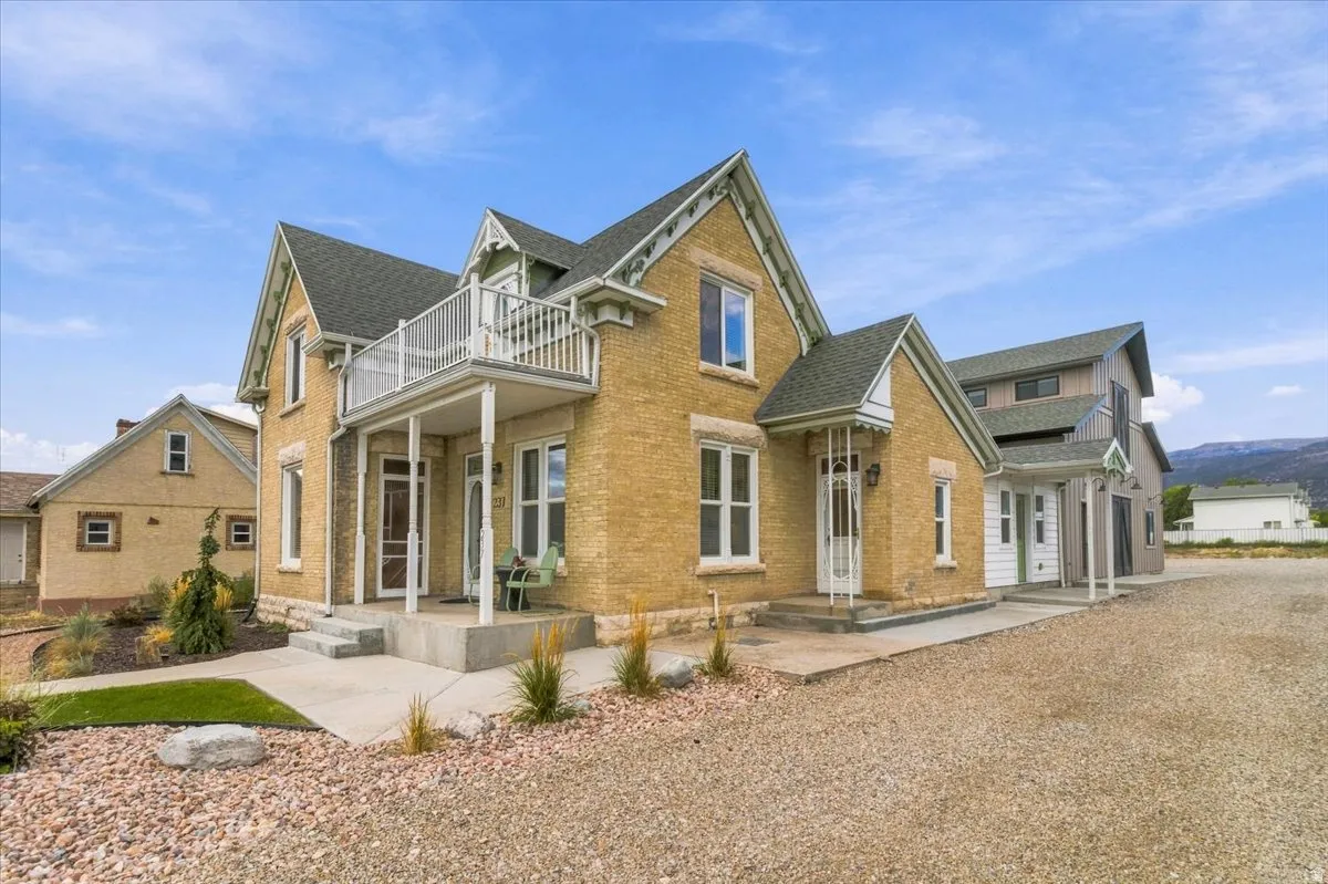 Light-toned brick exterior with white trim, featuring a second-story balcony and a covered front porch