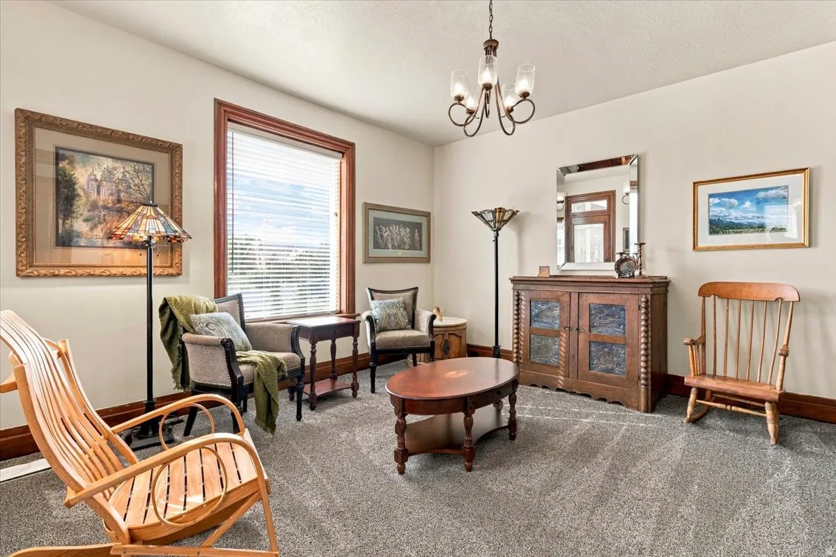 Light-colored wall paint with contrasting dark wood trim, textured gray carpeting, and a multi-light chandelier