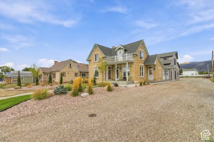 Elegant farmhouse-style residence featuring a cream-colored exterior with gabled rooflines and multiple chimneys
