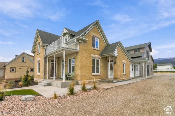 Light-toned brick exterior with white trim, featuring a second-story balcony and a covered front porch