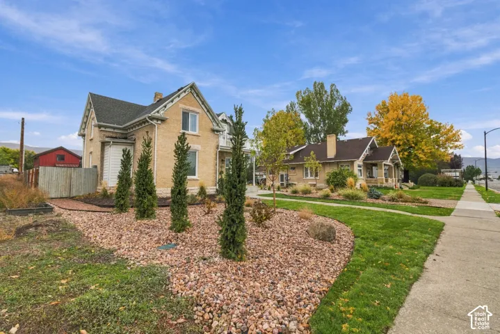 Brick exterior featuring decorative gables, stone foundation accents, and landscaped grounds with ornamental evergreen trees