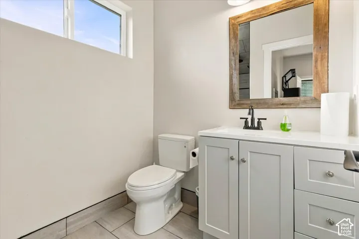 White vanity with light gray shaker-style cabinetry, a white countertop, and a dark-finish faucet