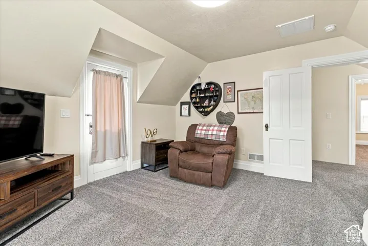 Sloped ceilings, recessed lighting, neutral wall tones, and gray carpeting