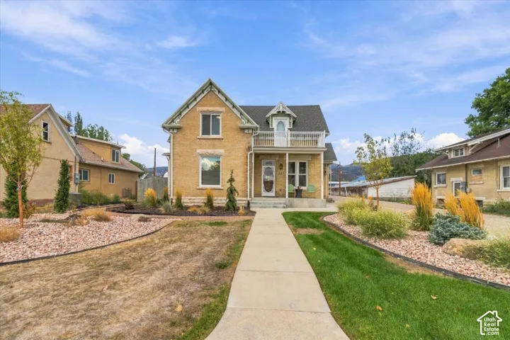 Classic Colonial-style residence with a distinctive peaked roofline and gabled entry, featuring a pale yellow exterior with contrasting trim and dark shale-colored roofing