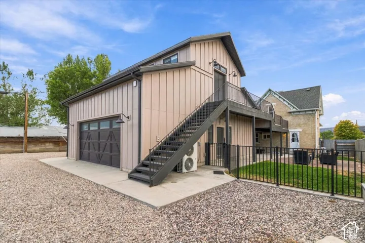 Board and batten exterior with an attached garage, upper-level balcony, and exterior staircase