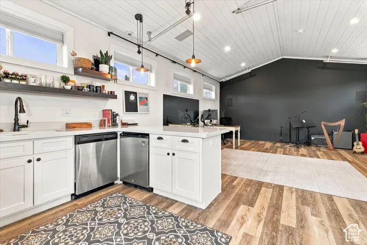White shaker cabinetry, stainless steel appliances, wood-finish flooring, white countertops, and vaulted ceilings