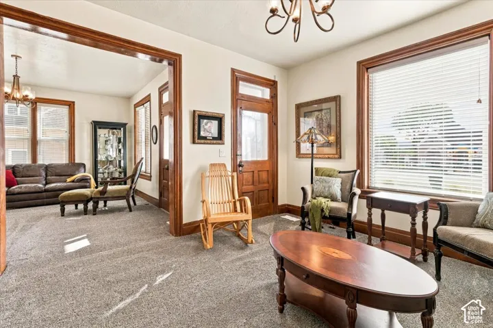 Carpeted living space featuring substantial wood trim, white walls, and a prominent window with horizontal blinds