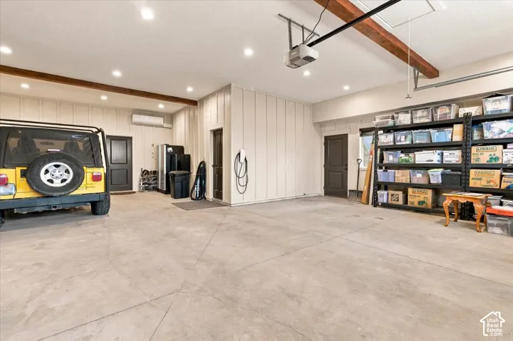 Spacious garage featuring a concrete floor, recessed ceiling lighting, exposed wood ceiling beams, and a mini-split climate control system