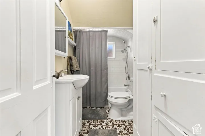 White paneled cabinetry, patterned tile flooring, and a shower-tub combination with subway tile surround