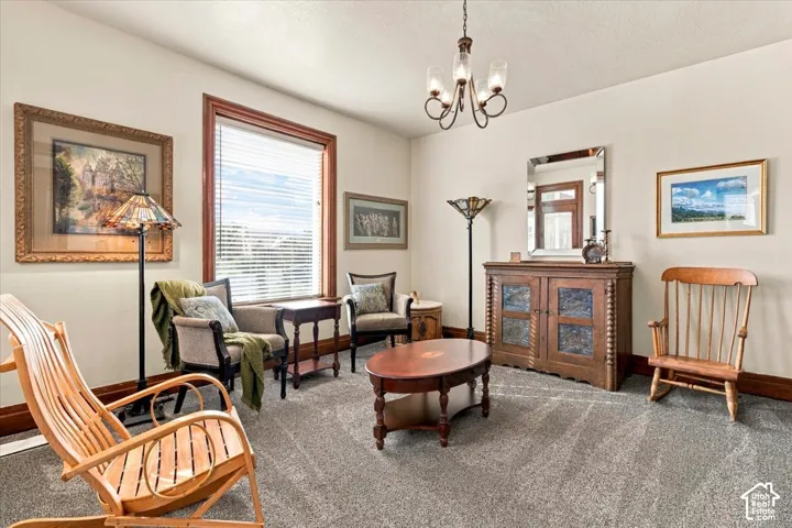 Light-colored wall paint with contrasting dark wood trim, textured gray carpeting, and a multi-light chandelier