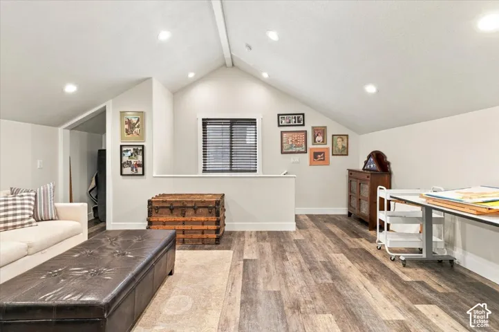 Vaulted ceiling with recessed lighting, wood-finish flooring, and a window with blinds