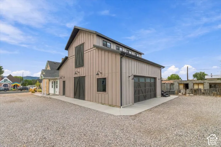 Barn-style exterior featuring vertical siding, a large overhead garage door, and multiple exterior lighting fixtures