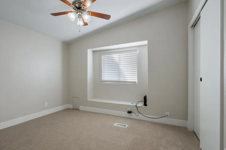 Sloped ceiling room featuring a ceiling fan with integrated lighting, a recessed window with blinds, and a built-in window bench