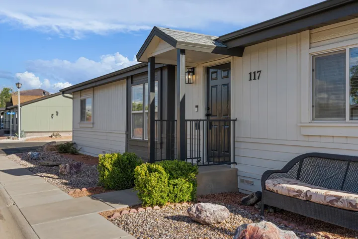 Exterior featuring a covered entryway, paneled front door, vertical siding, and low-maintenance landscaping