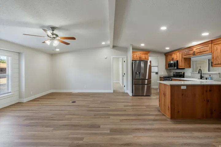 Open-concept living space featuring wood-finish flooring, recessed lighting, and a ceiling fan