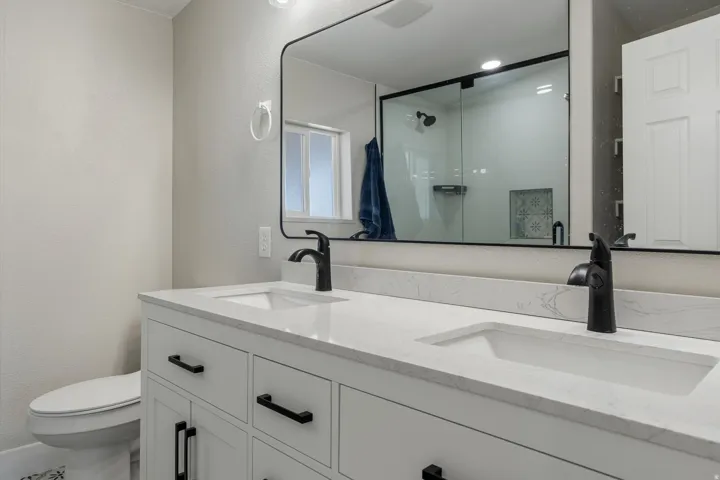 Dual vanity with white cabinetry, matte black hardware, and integrated sinks