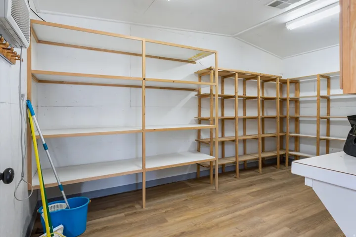 Extensive built-in shelving with wood-finish framing, wood-finish flooring, white walls, and overhead fluorescent lighting