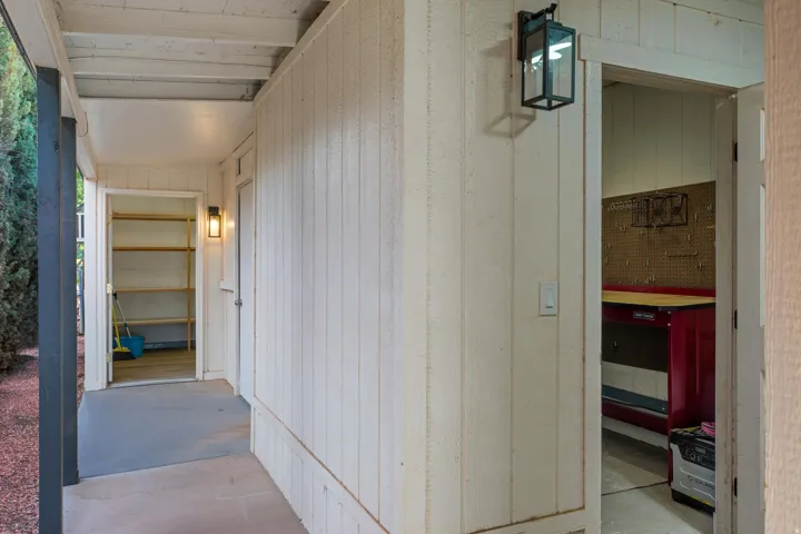 Covered patio with exposed beam ceiling, exterior wall lighting, and concrete flooring