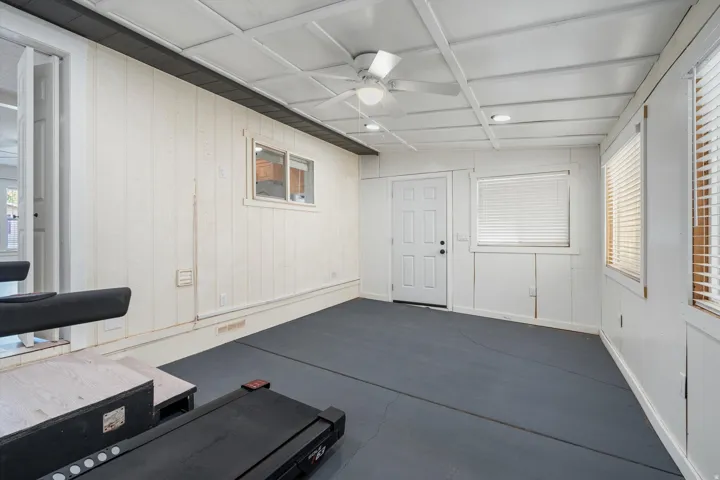 Painted paneling, multiple windows with blinds, ceiling fan, recessed lighting, and a paneled exterior door