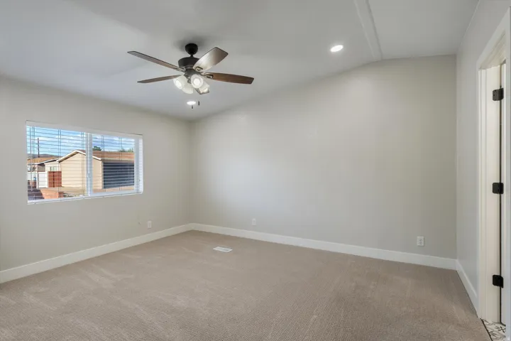 Carpeted room featuring a ceiling fan with integrated lighting, recessed ceiling lighting, a window with blinds, and a door with dark hardware