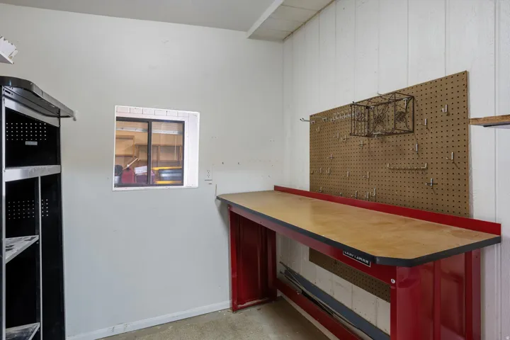 Work area featuring a red metal workbench, a small window, and a pegboard wall