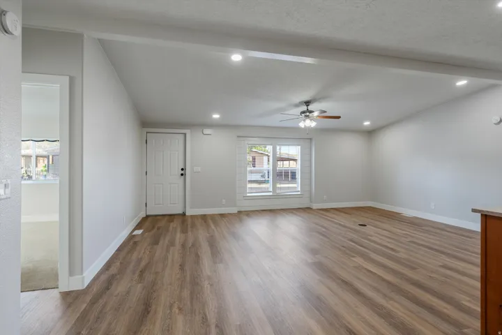 Vaulted ceiling, wood-finish flooring, recessed lighting, ceiling fan, and paneled entry door