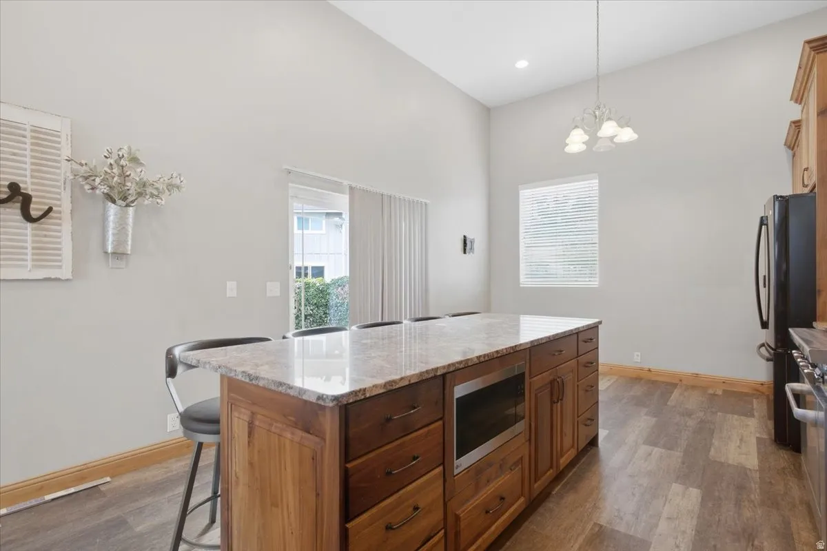 Kitchen island with a granite countertop, integrated microwave, and wood-finish cabinetry