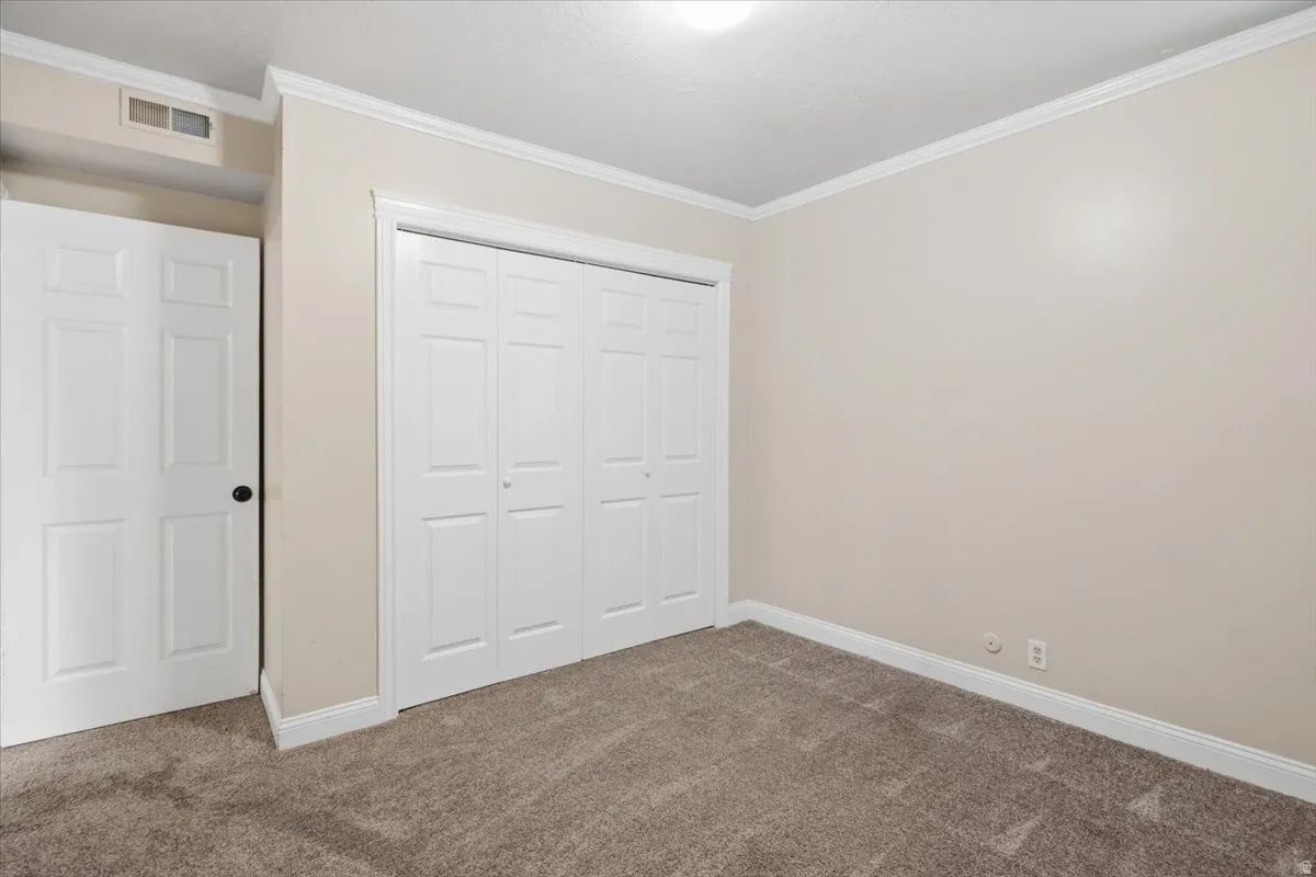 Neutral-toned walls, crown molding, and plush carpeting create a versatile interior