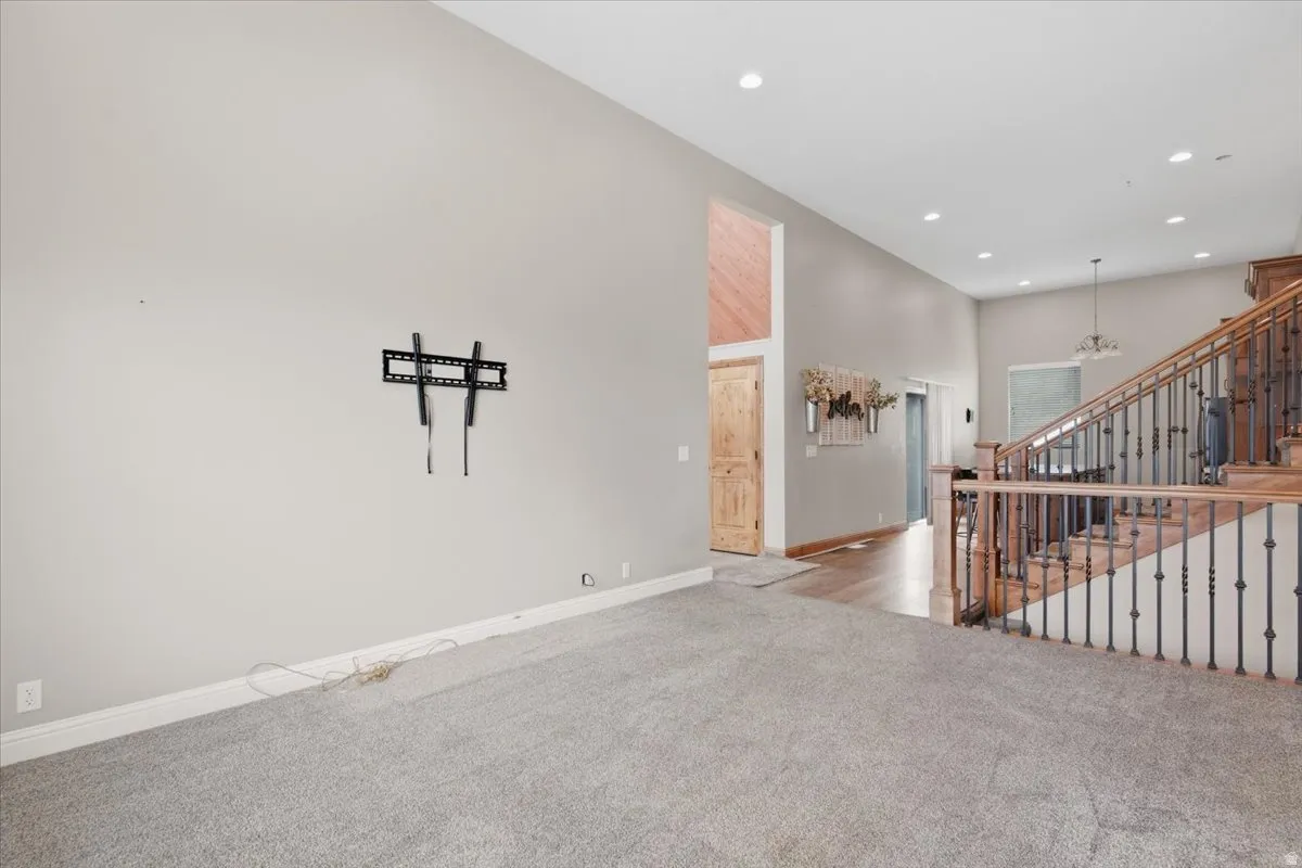 High ceilings with recessed lighting, wood-finish flooring, and a staircase featuring wood railings with wrought iron spindles