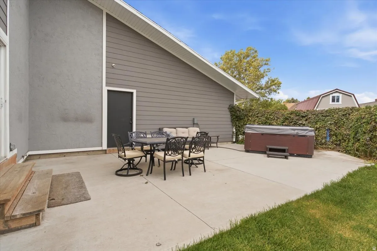 Expansive concrete patio with a hot tub and an exterior door
