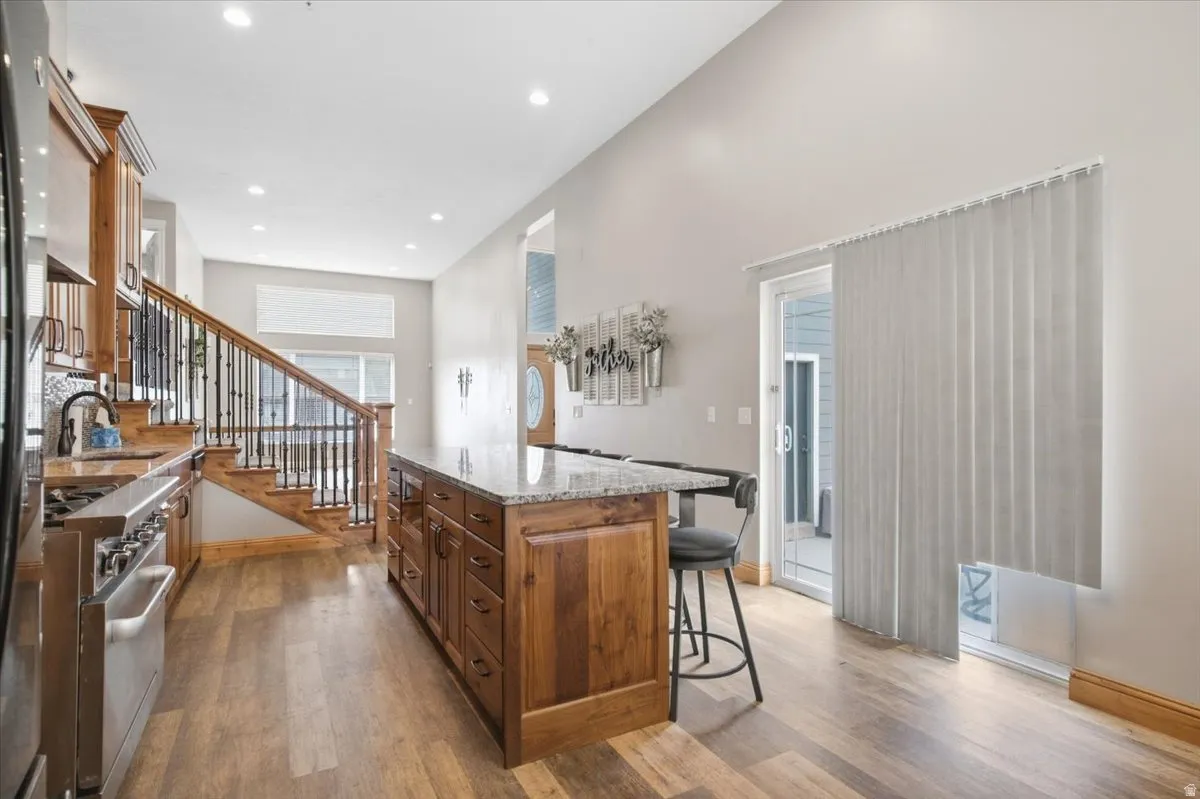 Kitchen with wood-finish flooring, stainless steel range, and a wood island featuring a stone countertop