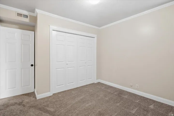 Neutral-toned walls, crown molding, and plush carpeting create a versatile interior