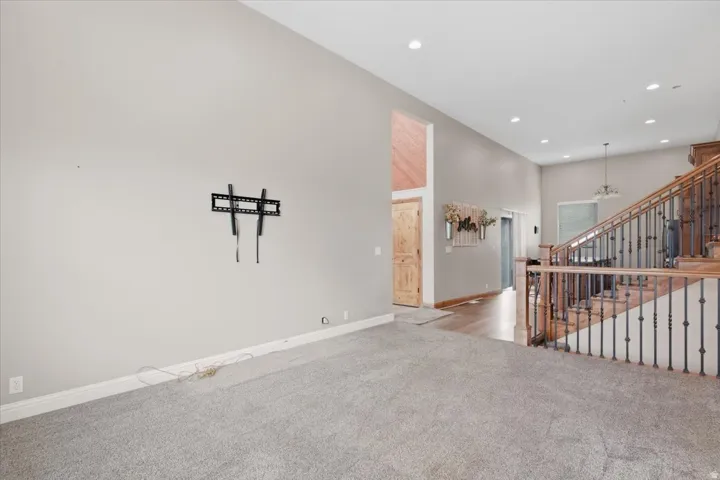 High ceilings with recessed lighting, wood-finish flooring, and a staircase featuring wood railings with wrought iron spindles