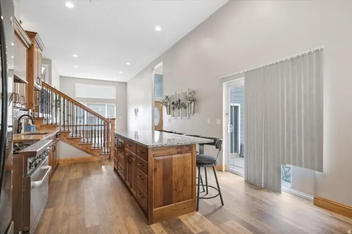 Kitchen with wood-finish flooring, stainless steel range, and a wood island featuring a stone countertop