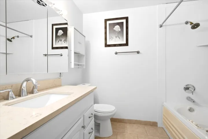 Bathroom featuring a single vanity with a surface-mounted sink, chrome faucet, and mirrored medicine cabinet